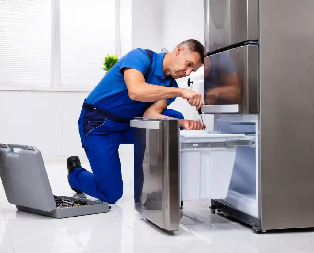 Technician performing refrigerator maintenance at home.
