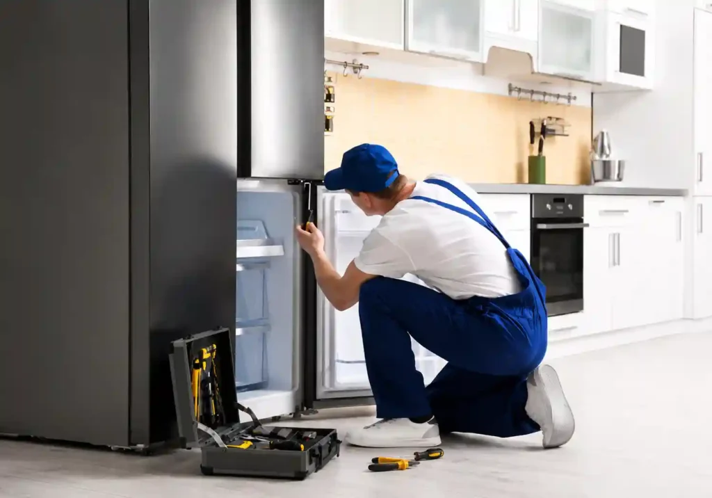 Technician repairing a home refrigerator.
