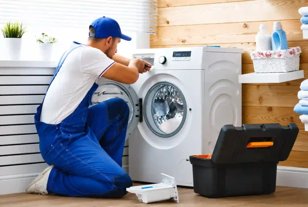 Technician repairing a front-load washing machine at home.